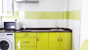 A compact kitchen with a microwave, sink, and washing machine. - Sea-view Apartment With Terrace (Conil de la Frontera)