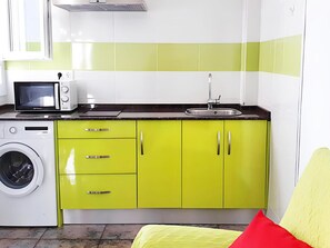 A compact kitchen with a microwave, sink, and washing machine. - Sea-view Apartment With Terrace (Conil de la Frontera)