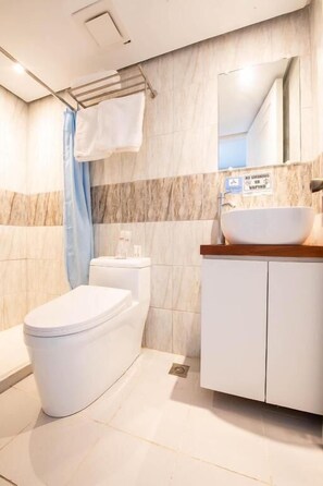 A modern bathroom with a white toilet, a sink with a wooden countertop, and a shower area with a blue curtain.