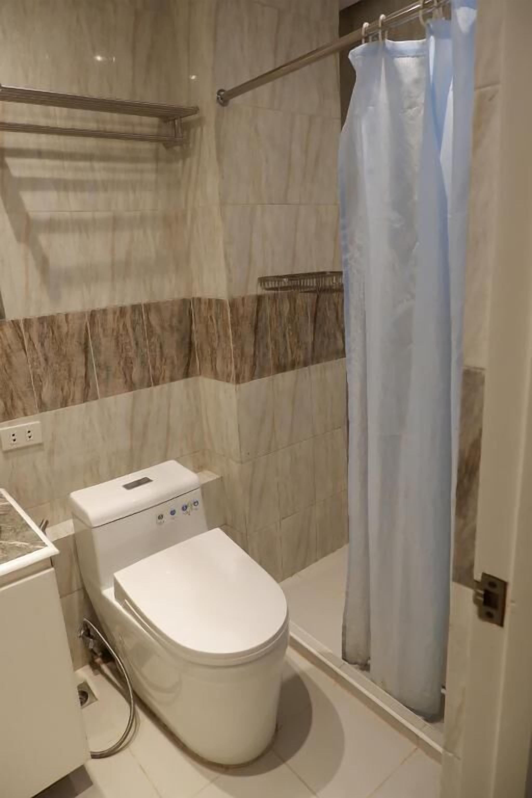 A modern bathroom with a toilet, shower, and a towel rack.