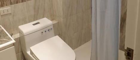 A modern bathroom with a toilet, shower, and a towel rack.