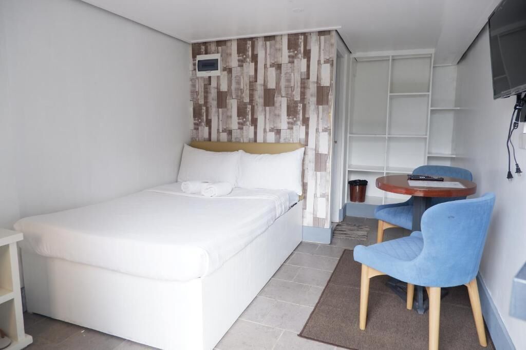 Una habitación de hotel con una cama, una mesita con una silla y un televisor en la pared.
