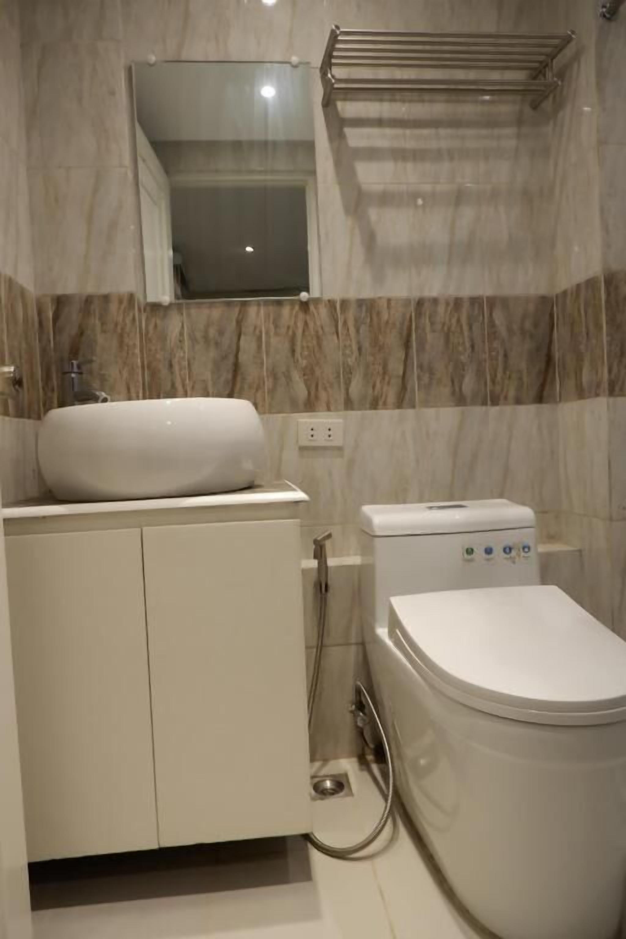 A bathroom with a white sink, toilet, and mirror.