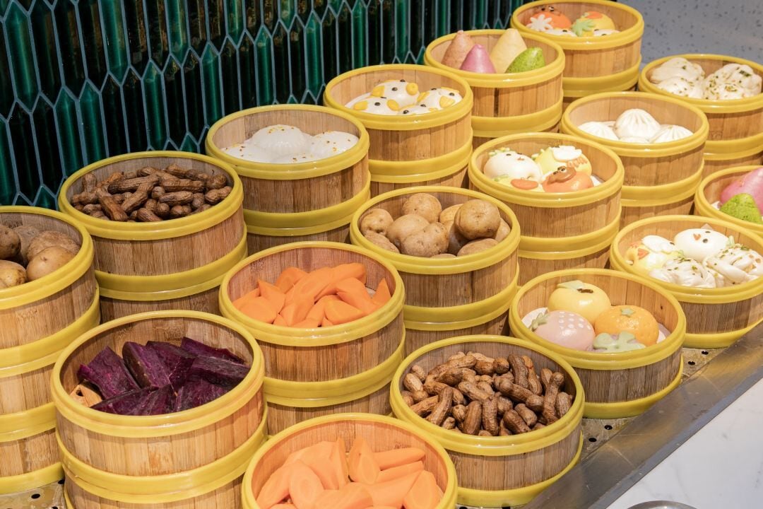 Une variété d’aliments présentés dans des récipients en bois dotés de couvercles jaunes.