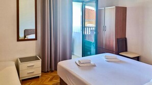 Een hotelkamer met een bed, een kledingkast, een bureau en een raam met gordijnen.