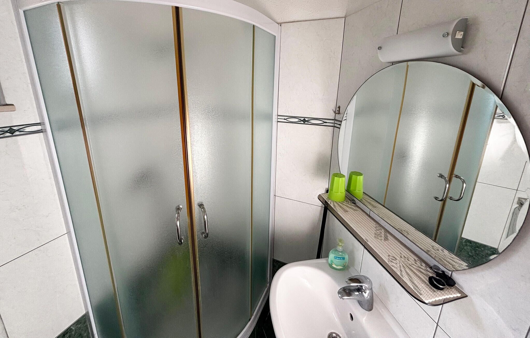 A bathroom with a white sink, a mirror, and a shower enclosure.