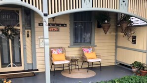 Une véranda avec deux fauteuils en osier, une petite table et une plante en pot.