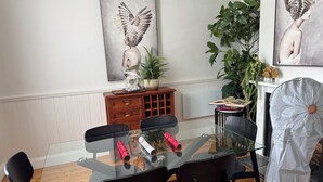 Un espace repas avec une table en verre, des chaises noires et des œuvres d’art accrochées aux murs.
