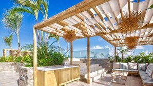 Eine Terrassengruppe im Freien mit einer Holzhütte, einer integrierten Bar und einer Sitzecke mit Sofa und Couchtisch.