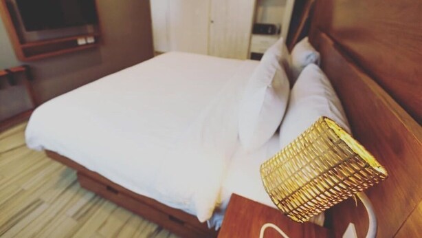Ein Hotelzimmer mit Bett, Fernseher und einem Holz-Kopfteil.