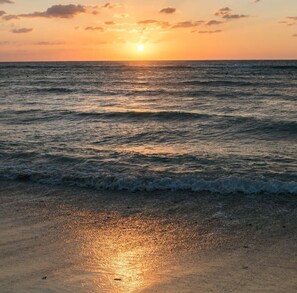 A beach at sunset with waves gently lapping onto the shore. - Stylish Apt w/ In-Unit Laundry • Rooftop Pool (Playa del Carmen,)