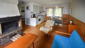 A cozy living room with a fireplace, a blue sofa, and a wooden coffee table. - Amazing home in Ekshärad with WiFi (Ekshärad)