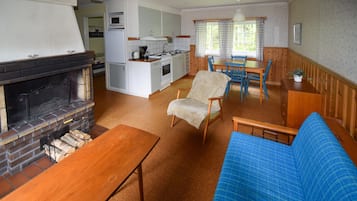 Ett mysigt vardagsrum med en öppen spis, en blå soffa och ett soffbord i trä.