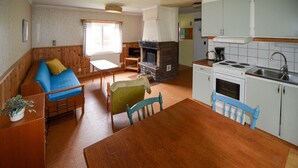 A cozy room with a wooden sofa, a dining table, and a kitchen area with a stove and sink. - Amazing home in Ekshärad with WiFi (Ekshärad)