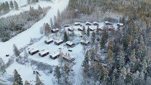 En gruppe træhytter i et sneklædt skovlandskab.