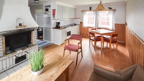 A compact kitchen with a microwave, stove, and sink. There is a dining area with a table and chairs, and a fireplace with a plant on the mantel. - Stunning home in Ekshärad with WiFi (Ekshärad)