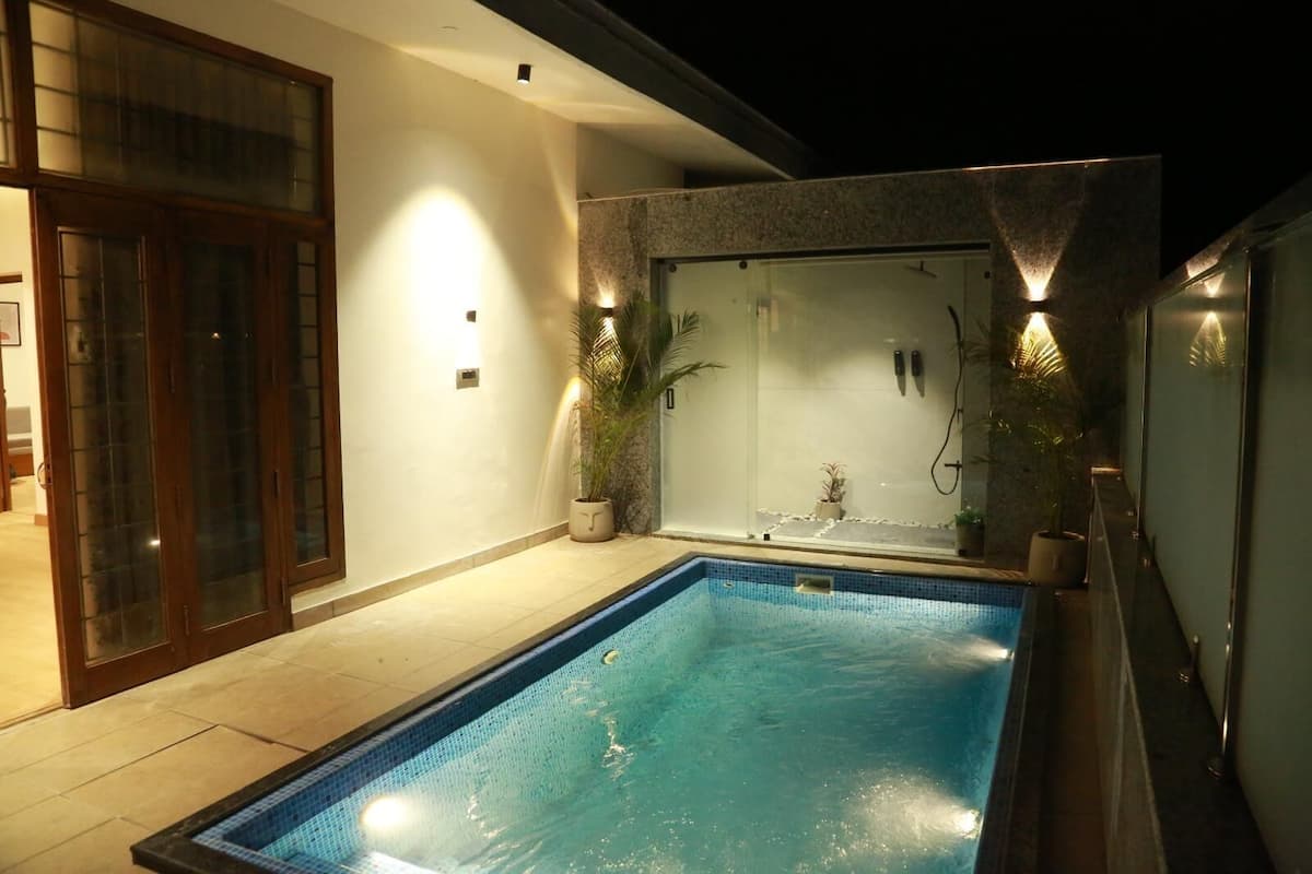 A swimming pool with a glass enclosure, potted plants, and a tiled floor.
