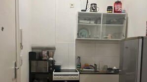 Une cuisine compacte équipée d’une cuisinière, d’un four, d’un réfrigérateur et d’un petit plan de travail sur lequel sont disposés divers objets.