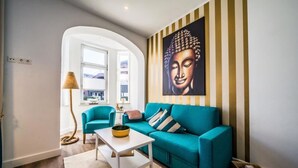 Uma sala de estar moderna com um sofá azul-turquesa, uma mesa de centro branca e uma grande pintura de Buda na parede.