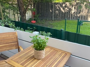 Una mesa de madera con una maceta tejida en un balcón.