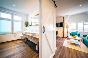 Ein modernes Badezimmer mit zwei Waschbecken, einem großen Spiegel und Holzboden.