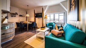 Un appartement moderne comprenant un coin repas, un canapé de couleur turquoise et une cuisine avec des meubles en bois.