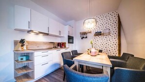 Une cuisine moderne avec des meubles blancs, un plan de travail en bois et un coin repas comprenant une table et des chaises.