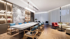 A modern interior with a long dining table, wooden chairs, a red chair, a round table, and a sofa. - ECHENG Hotel Xiaogan East Station Yintai City (Xiaogan)