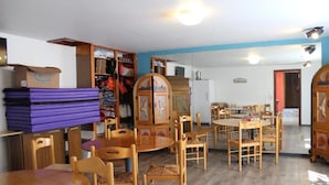 A room with wooden furniture, including a dining table and chairs, a cabinet, and a mirror.