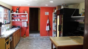 A compact kitchen with a red wall, wooden cabinets, a sink, and a stove.
