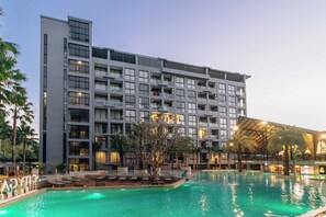 A hotel with a large swimming pool, multiple balconies, and a modern architectural design. - Condo with Full Facilities C255 (Kamala)