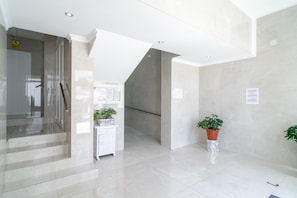 A modern interior with a staircase, a white cabinet, and potted plants. - Apartment in Nerja With Sea Views & Pool (Nerja)