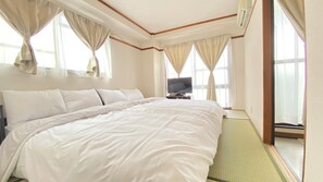 A hotel room with a large bed, a television on a nightstand, and windows with curtains. - 4 Units Same Floor, Tsutenkaku Tower - Namba Room (Ebisu Higashi, Naniwa-ku, Osaka City)