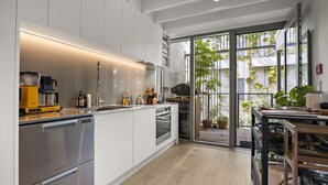 Une cuisine moderne dotée d’appareils électroménagers en acier inoxydable, d’un four encastré et d’une grande fenêtre donnant sur un jardin.
