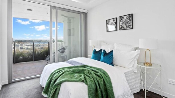 Une chambre à coucher avec un lit, un balcon et deux œuvres d’art murales.