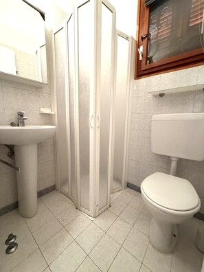 Un baño con inodoro, lavamanos y cabina de ducha de vidrio.
