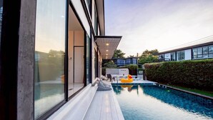 A modern building with a swimming pool, large windows, and a well-maintained garden. - Emery Pool Villa Pattaya
We are welcome your family,friend and your pet (Banglamung)