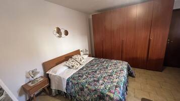 Ein Schlafzimmer mit Bett, einem Holzschrank, einem Nachttisch und einer Wandleuchte.