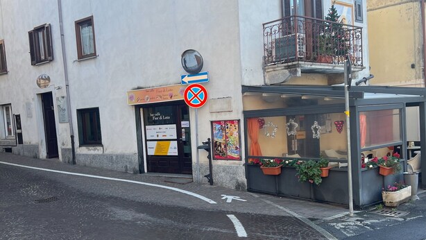 A building with a ground-floor shop, a no parking sign, and a cobblestone street. - The House of Anastasia (Taino)