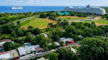 A coastal area with a large cruise ship docked, a soccer field, and residential buildings.