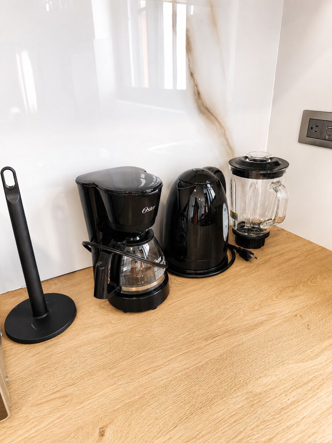 A kitchen counter with a coffee maker, a kettle, and a blender.
