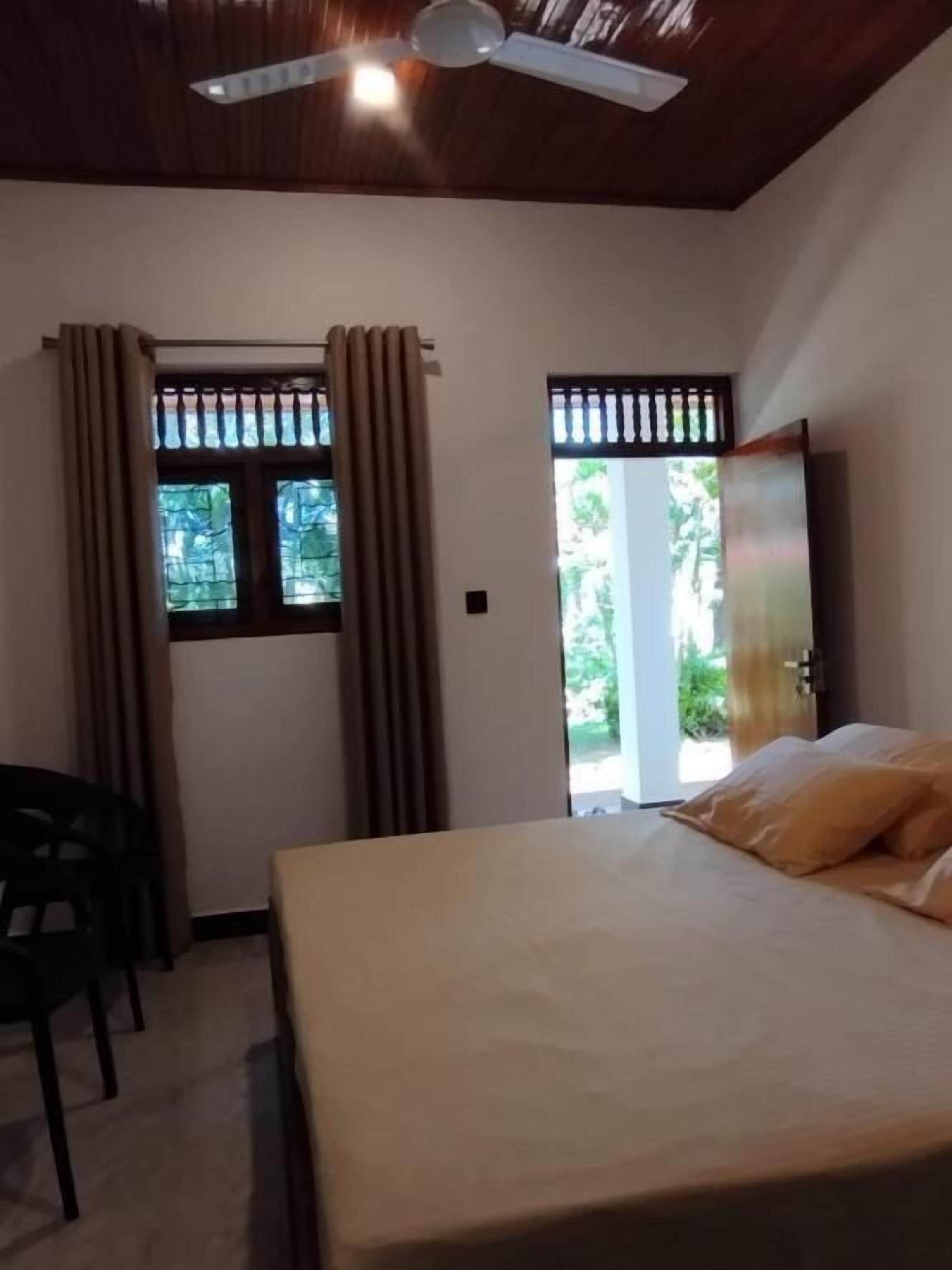 A hotel room with a bed, a ceiling fan, and a window with curtains.