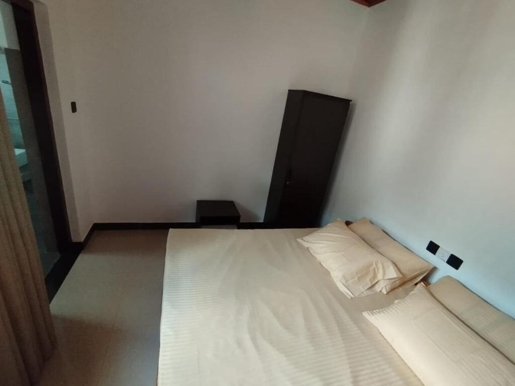 A bedroom with a bed, a nightstand, and a wardrobe.