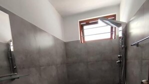 Un baño moderno con un lavamanos rectangular, inodoro y zona de ducha.