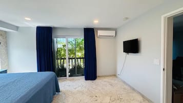 A hotel room with a bed, a TV, and a sliding glass door leading to an outdoor area.