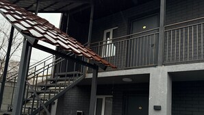 Un edificio de varios pisos con una escalera metálica que lleva a un balcón.