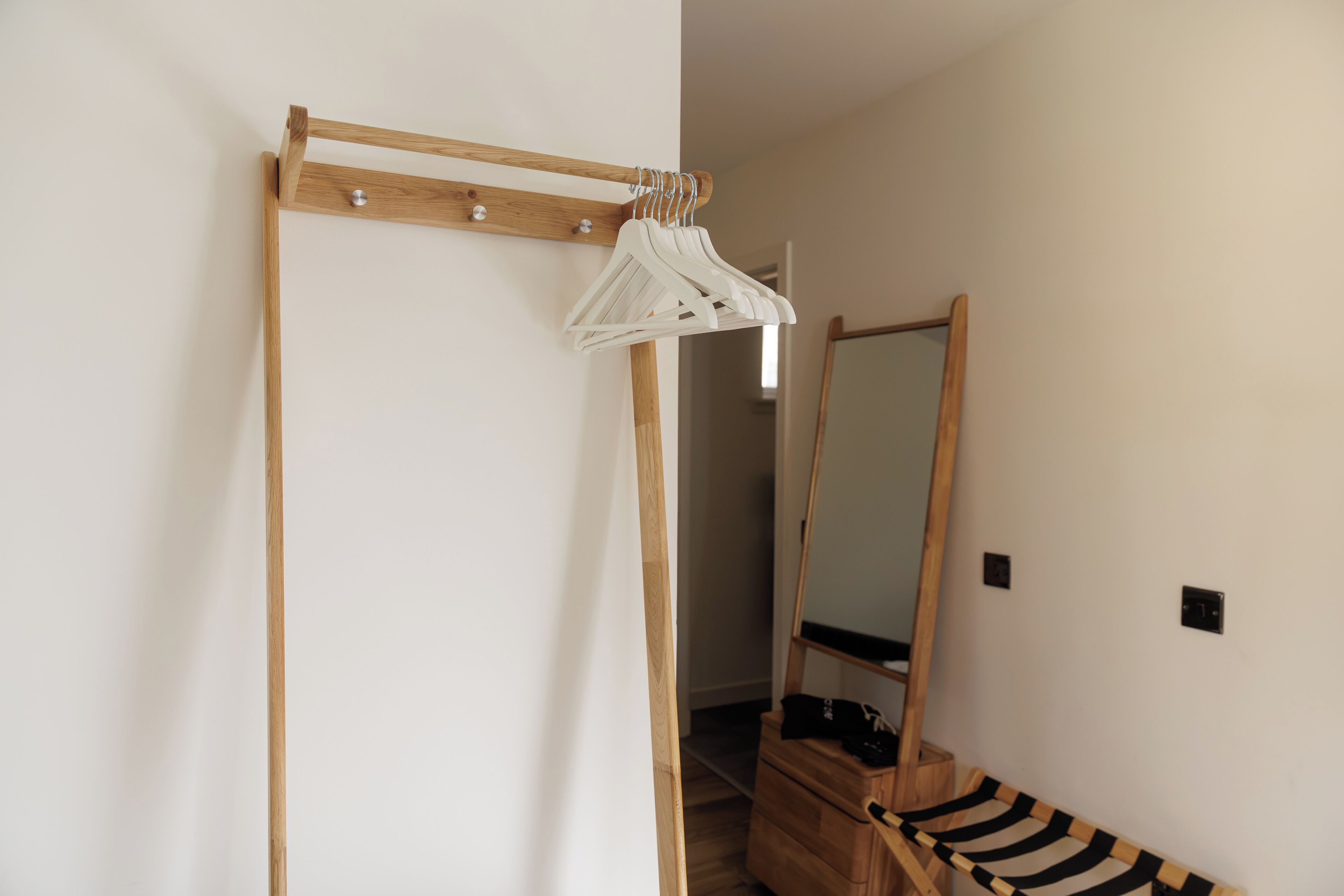 Une pièce comprenant une armoire en bois, un miroir et un portant à vêtements.