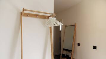 Une pièce comprenant une armoire en bois, un miroir et un portant à vêtements.