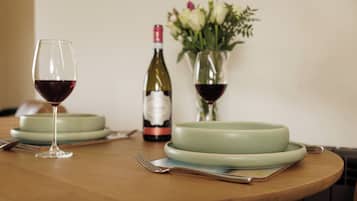 Una mesa de comedor con una botella de vino, dos copas de vino, un florero con flores y un plato.