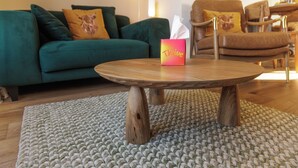 A living room with a green sofa, a brown leather chair, a wooden coffee table, and a textured rug. -  Cosy Cottage with sea view, 10 mins from Portree (Portree)